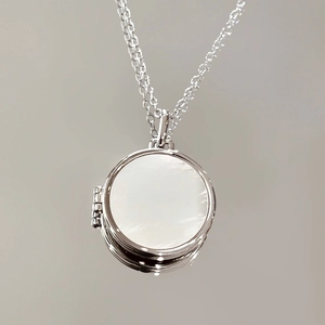 Elegant silver necklace featuring a round pendant with white shell inlay on a neutral background