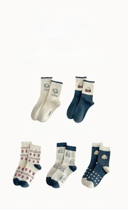 Gros plan de cinq paires de chaussettes en coton avec chiens, étoiles et motifs floraux