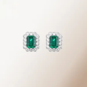 Macro view of emerald stud earrings with halo of white zircons in silver setting