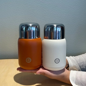 Detail view of compact insulated tumblers in orange and white with mirror-finish lids