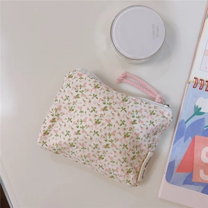 Detail of floral cotton mini pouch featuring pink flowers, white zipper and woven puller