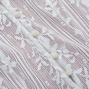Gros plan sur la dentelle blanche avec des boutons ronds en velours sur une robe
