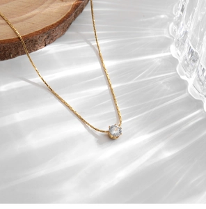 Detail of 18K gold-plated bamboo chain necklace with a sparkling six-prong zircon pendant