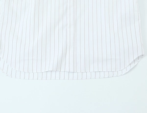 Detail of the curved hemline and fine stitching on a white striped cotton shirt