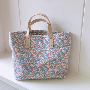 Dettaglio della borsa tote in cotone floreale con manici in pelle e rivetti