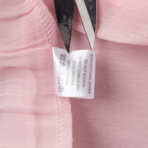 Detailed macro view of the washing label and pink chiffon fabric texture on the dress