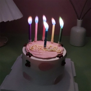 Close-up van creatieve verjaardagskaarsen met gekleurde vlammen die op een feesttaart branden