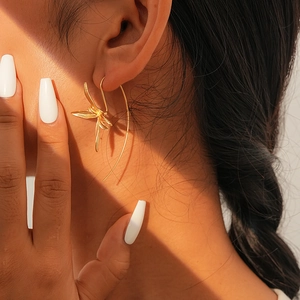 Close-up of elegant gold iris flower earrings worn by a model in warm light