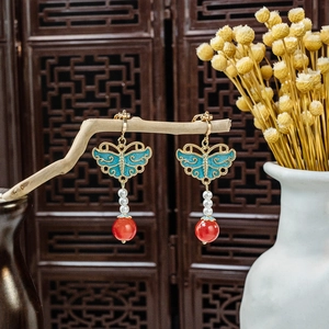 Detail of blue cloisonne butterfly earrings with pearls and red beads in vintage style