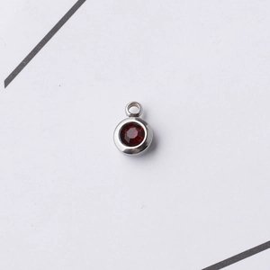 Macro view of a 6.5mm stainless steel pendant featuring a round red birthstone crystal