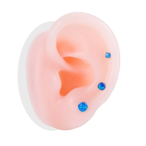 Golden push-in flat back labret studs with blue opal stones shown on an ear model