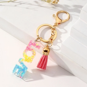 Macro view of rainbow resin letter keychain with star glitters and pink tassel