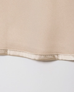 Vue macro de la jupe en satin champagne montrant les coutures raffinées et la texture du tissu