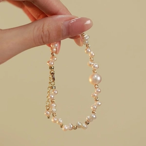 Dettaglio del bracciale di perle intrecciate con perline dorate e chiusura a moschettone