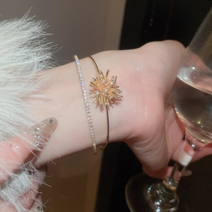Detail of gold fireworks bangle and zircon tennis bracelet with a plush cuff and wine glass