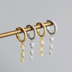 Detail of gold and silver S925 earrings with geometric zircon tassel pendants on a stand