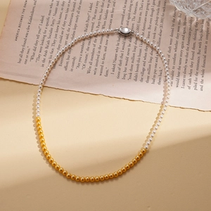 Detail of necklace featuring half white pearls and half gold beads on vintage book pages