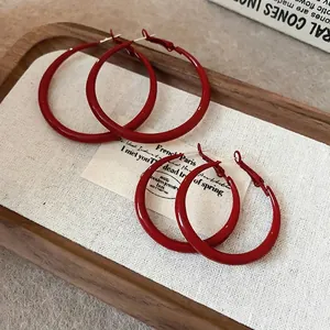 Set of two pairs of vintage red hoop earrings in different sizes on a wooden tray