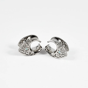 Detail view of silver hollow moon-shaped ear plugs with blue opal inlays for ear piercing