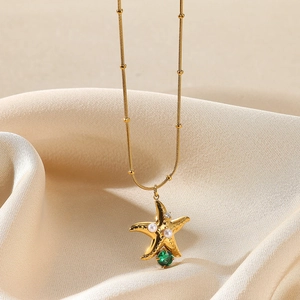 Detailed close-up of golden starfish pendant necklace with pearls and green gemstone