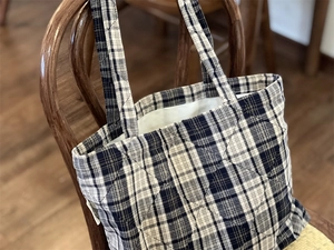 Detail of navy blue quilted plaid tote bag showing diamond stitching and fabric texture