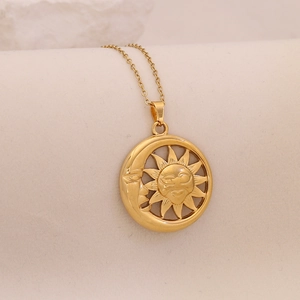 Macro view of golden sun and moon face pendant on a stainless steel necklace