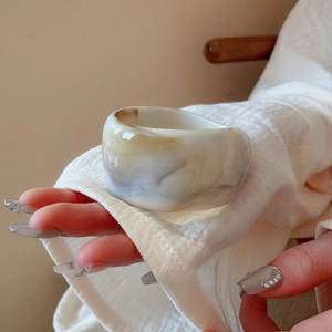 Detail of wide resin bangle with marble texture and amber swirls on hand