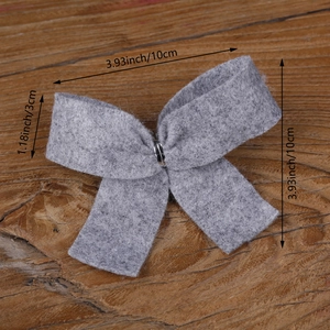 Gray felt Christmas tree bow decoration with silver metal clip on wooden background