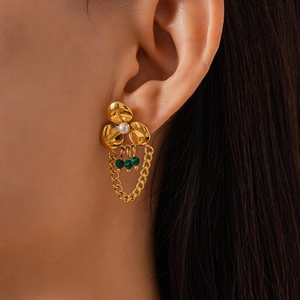 Close-up of gold flower earrings with pearl center and green bead tassels on model