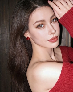 Close-up of red flower stud earrings with gold center, worn on ear for an elegant style