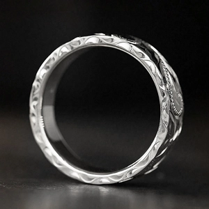 Macro shot of silver embossed floral pattern and vintage scroll engraving on wide band ring