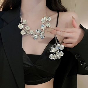 Detail of silver leaf necklace and earrings set worn by a model in a black blazer