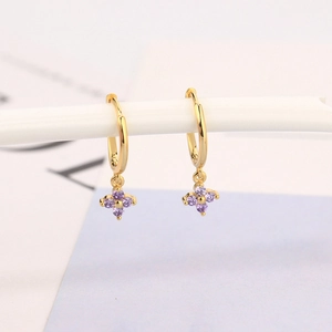 Golden hoop earrings featuring a floral pendant with purple zircon stones on a white stand