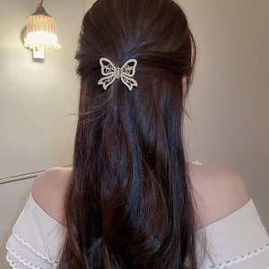 Detail shot of golden butterfly claw clip with hollow wings and rhinestones in hair