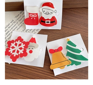 Detail of Christmas hair clips featuring Santa and tree motifs on a white display card