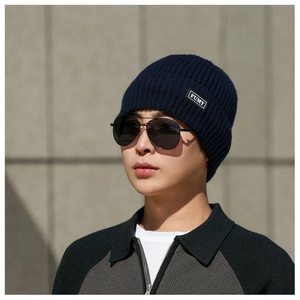 Close-up of navy knit beanie with ribbed texture and FUMY logo patch for outdoor wear