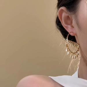 Close-up of luxury gold fan-shaped drop earrings with zircon fringe on a model