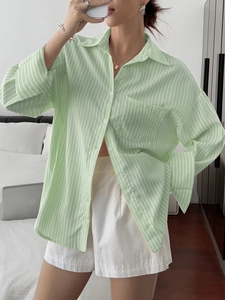 Detail of green and white striped long-sleeve loose shirt with front chest pocket