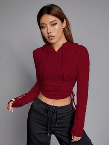 Detail of burgundy slim fit hooded crop top showing knit texture and waist tie design