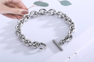 Detail of silver stainless steel curb chain with OT toggle clasp on white surface