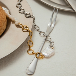Artistic detail of a two-tone pearl necklace with gold and silver links on a plate