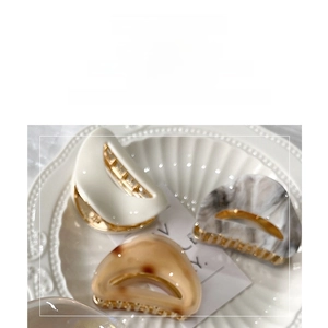 Detailed shot of cream leopard acetate hair claws in various colors on a porcelain plate