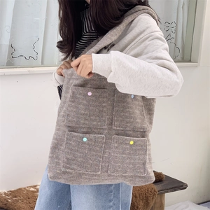 Detail view of large grey felt tote bag featuring four colorful front pockets with buttons