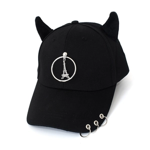 Detail of black baseball cap with devil horns and Eiffel Tower charm in punk style