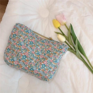 Close-up of floral print cotton makeup bag with tulip decor on a quilted background