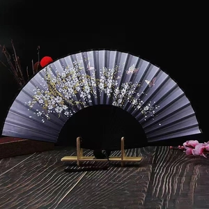 Detailed close-up of a Japanese folding fan featuring cherry blossom and butterfly patterns