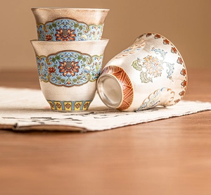 Exquisite detail of silver-gilt teacups featuring colorful floral enamel patterns