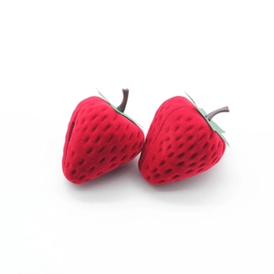 Detailed view of two red flocked strawberry jewelry boxes with green leaf accents