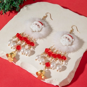 Macro detail of Christmas earrings with plush ball, Santa resin charm and red beads