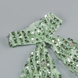 Detail of mint green sequin halter dress with floral rhinestones on mesh fabric